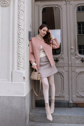 a lady in a beige knit top, a pink jacket and an A-line mini skirt
